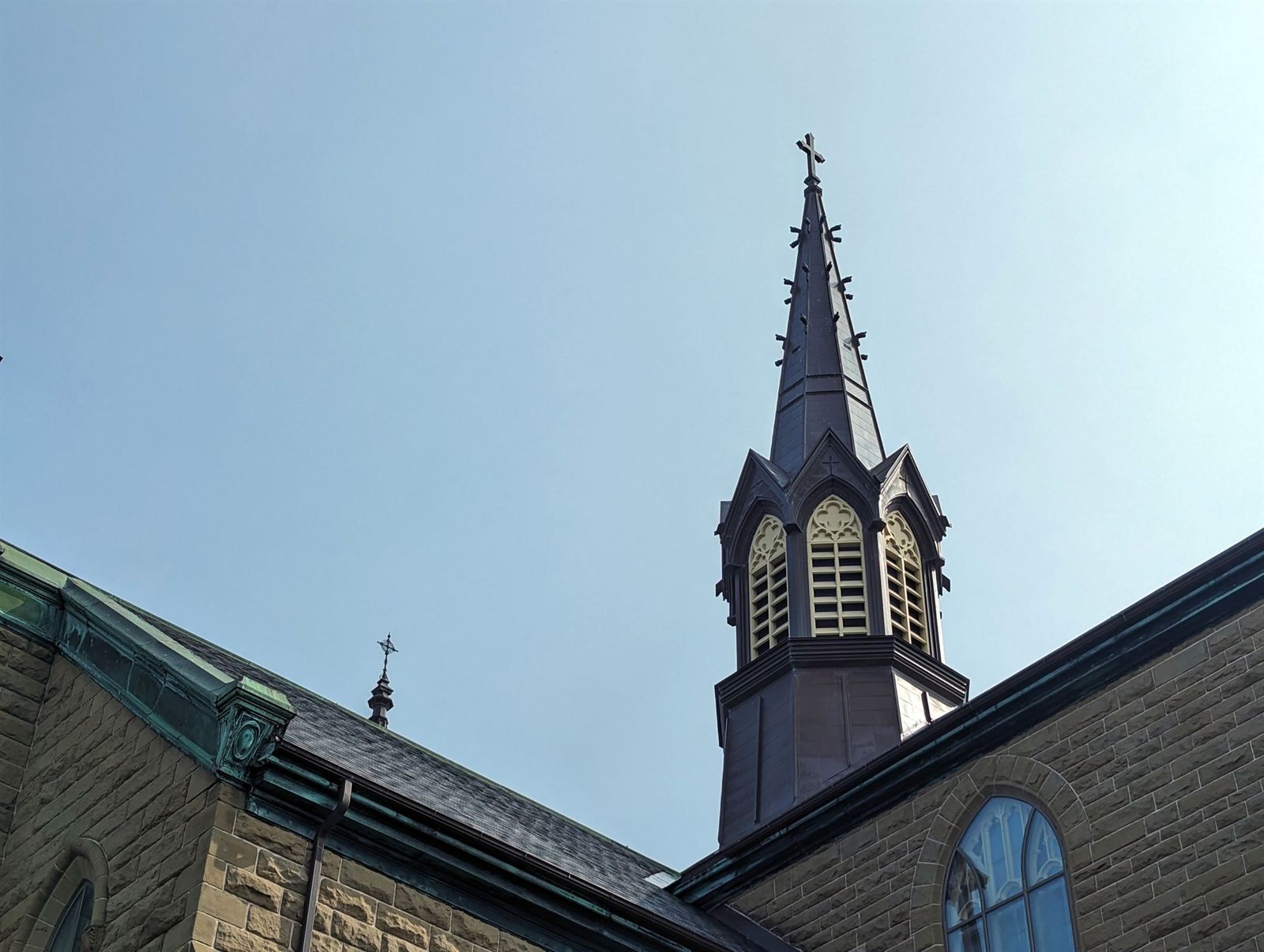 Dark slate spire and stone walls of a church in Charlottetown against a clear sky