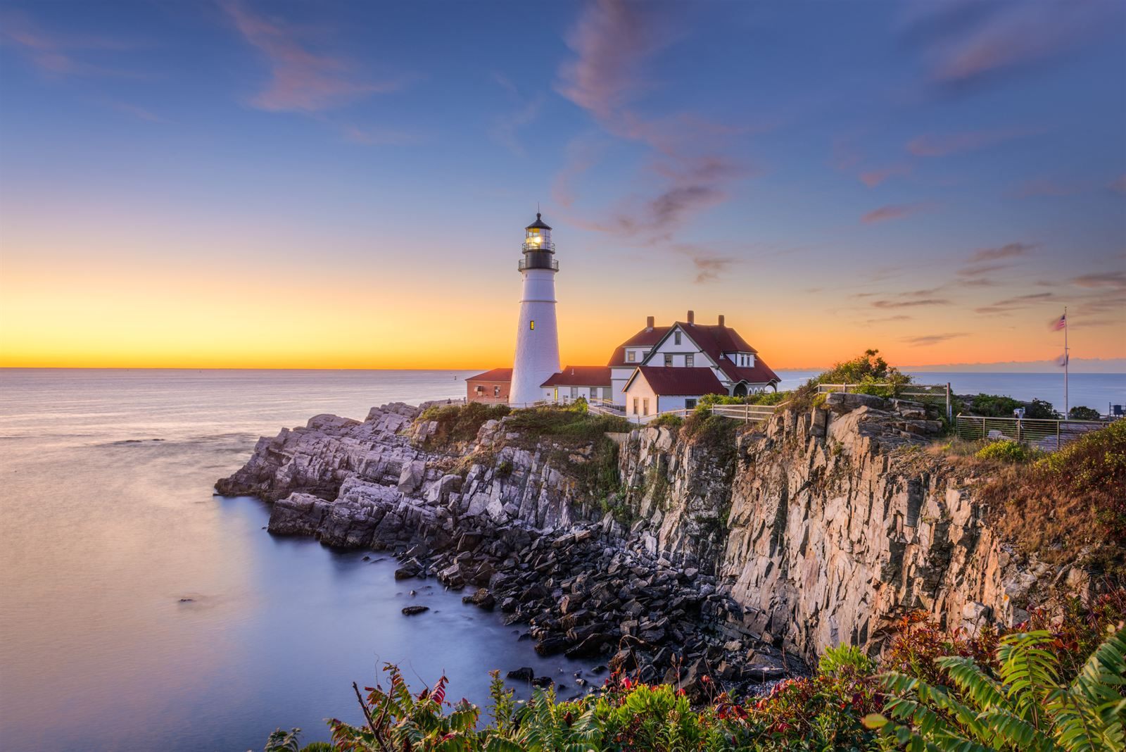 Portland Head Light and its red-roofed keeper's house on a rocky point at sunrise, Maine