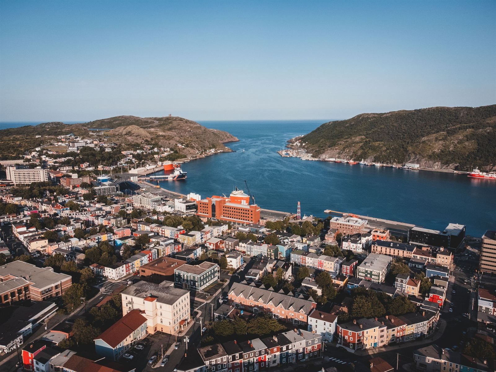 Aerial view of downtown St. John's, Newfoundland, with colorful row houses and the harbor narrowing to the sea between hills